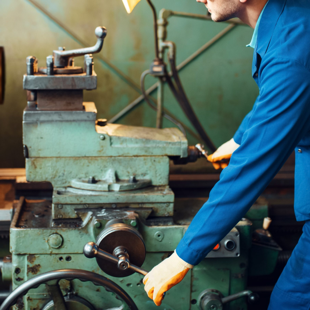 worker-in-uniform-and-helmet-works-on-lathe-2021-08-28-02-49-31-utcSS-scaled